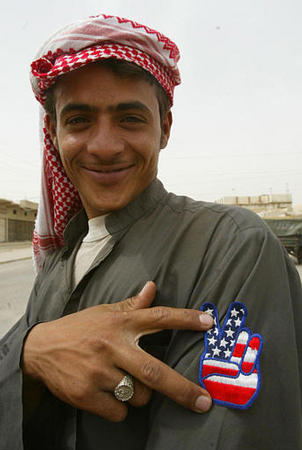 A young man shows off a badge with the U.S flag on it as the British Royal Air Force Regiment patrol, southern Iraqi town of Safwan, April 8, 2003.
